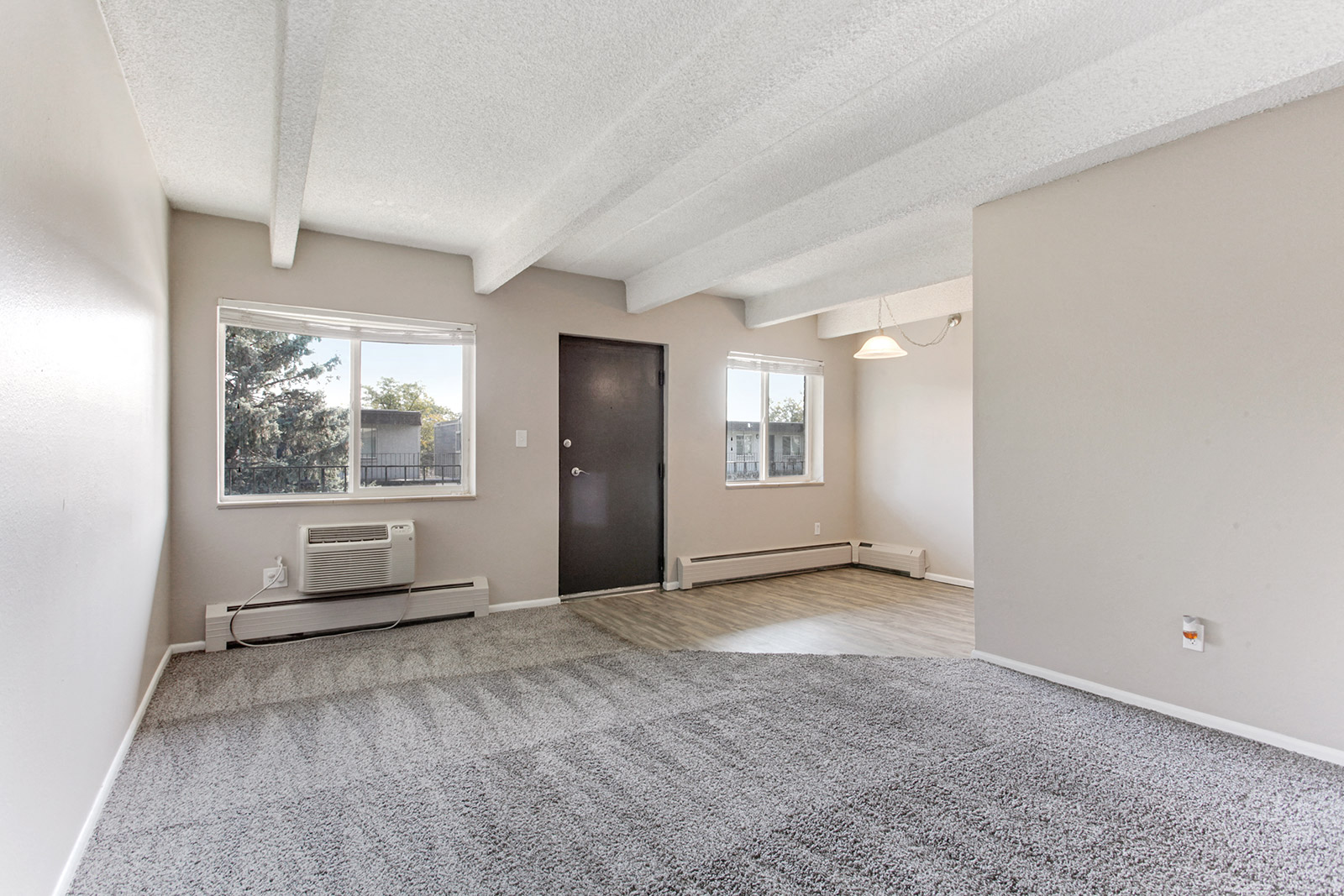 an empty living room with carpet and a door to a hallway