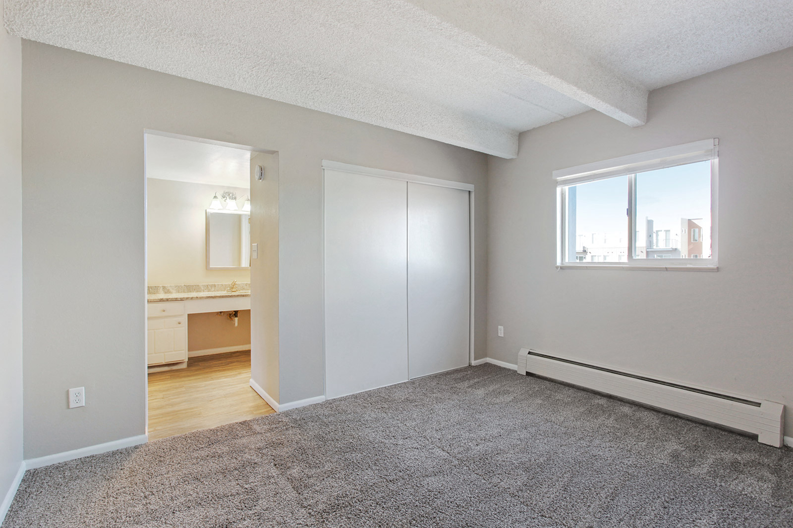 an empty living room with a window and a door to a bathroom