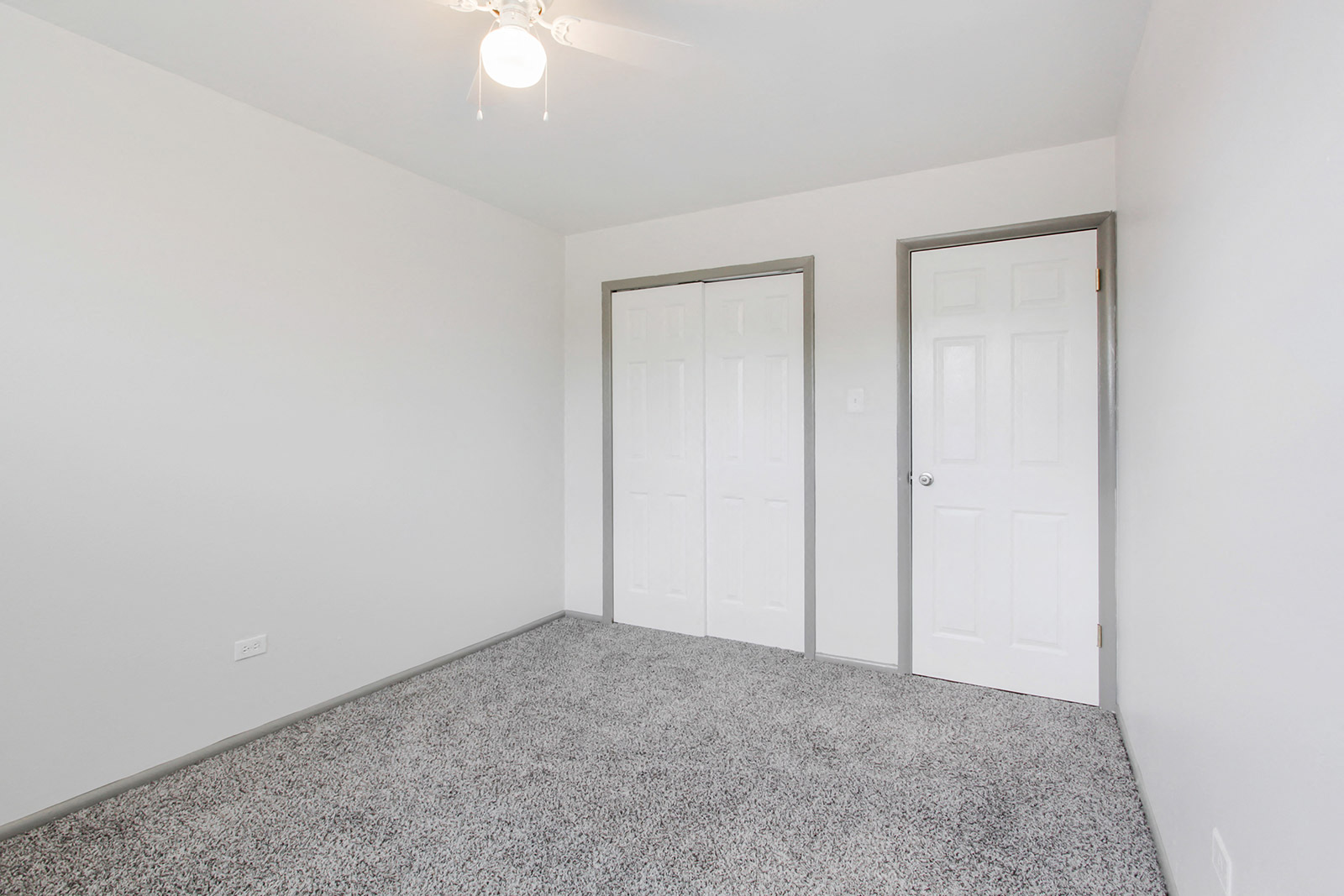 a bedroom with white walls and carpet and white doors