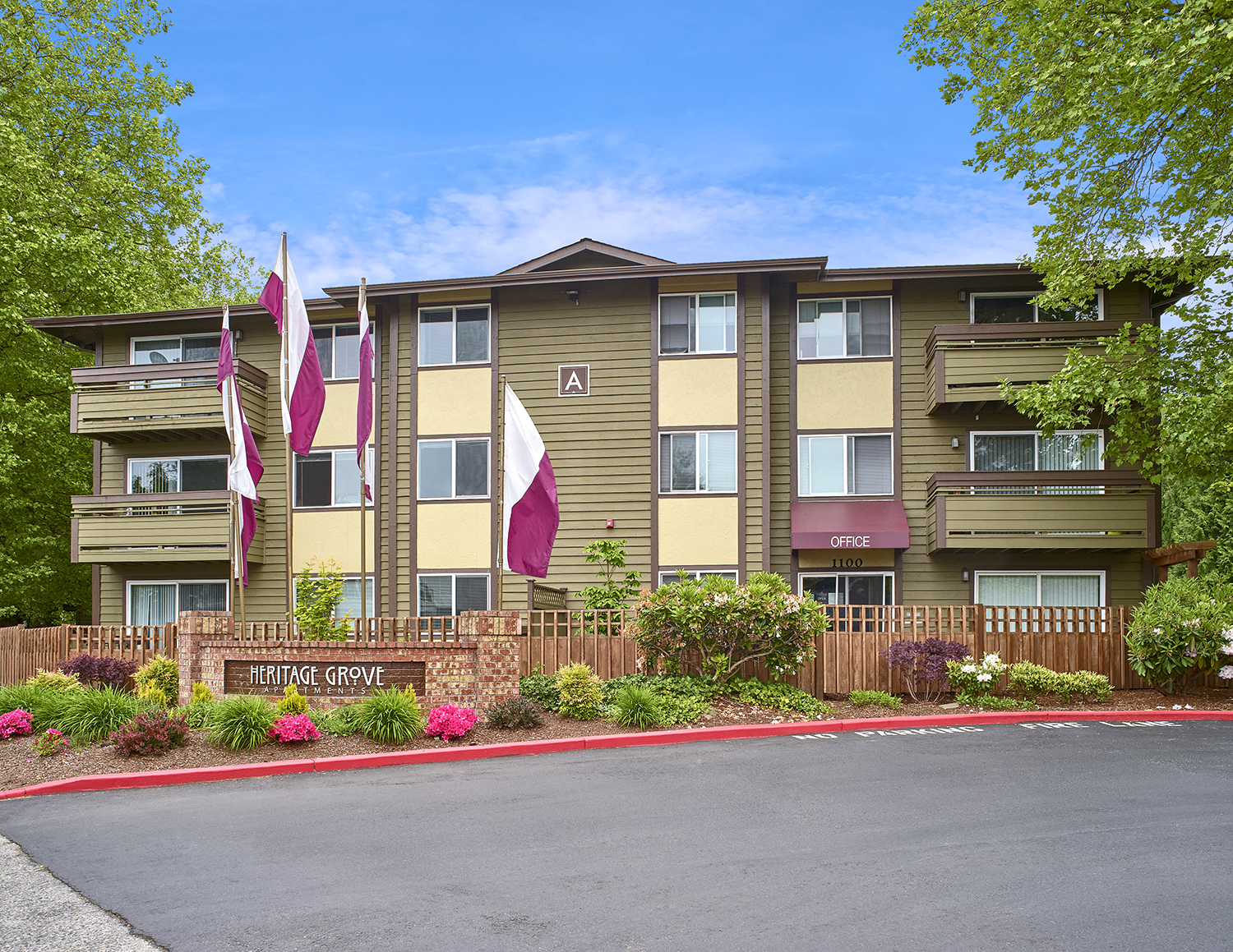 Exterior view of manicured grounds and building, and blue skies in the background at Heritage Grove, Renton, WA.