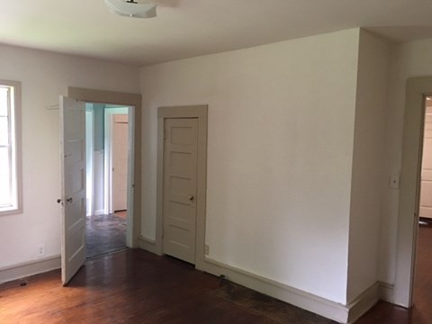an empty living room with white walls and a wood floor