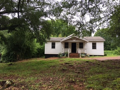 a small white house with a yard and some trees
