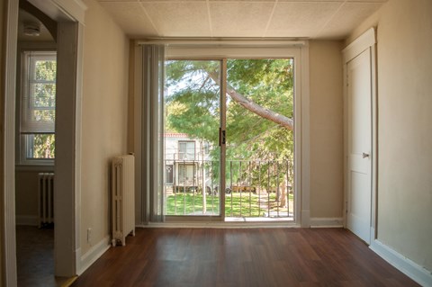 an empty living room with a sliding glass door to a backyard