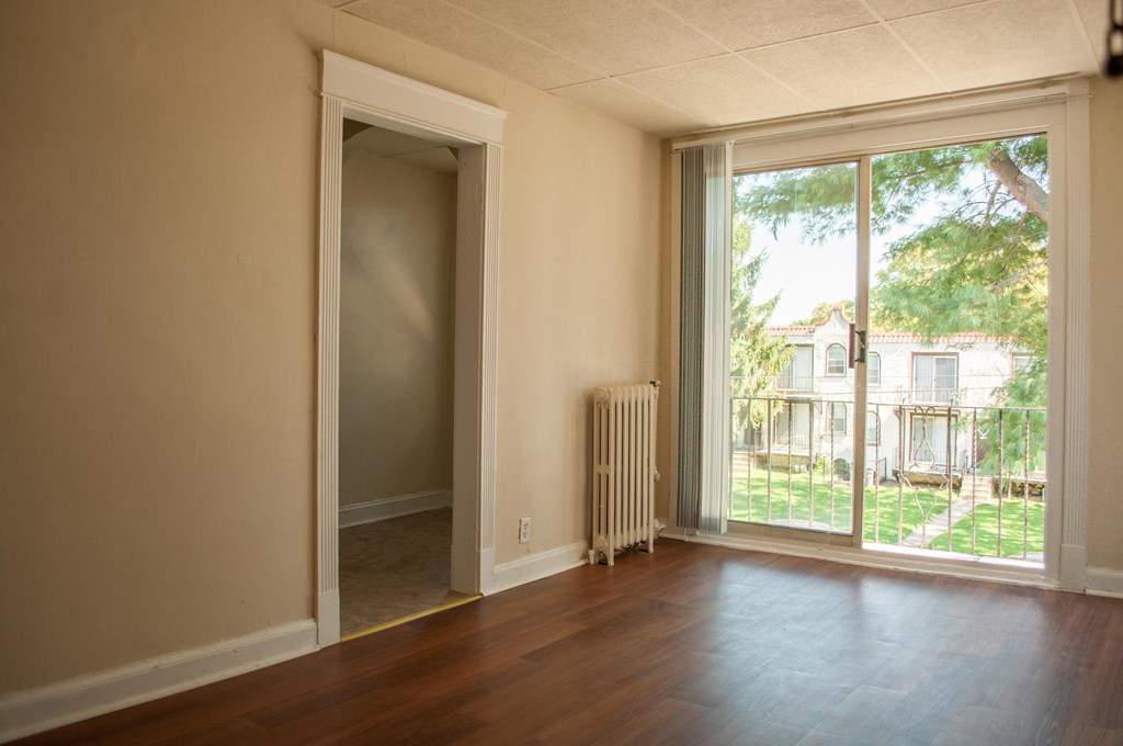 an empty living room with a large window and wood floors