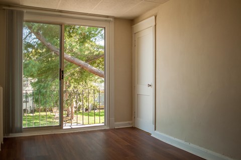 an empty living room with a sliding glass door to a backyard