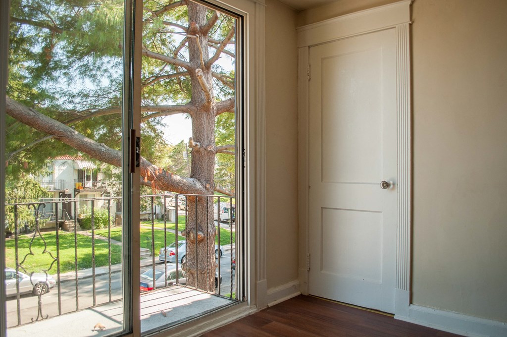 a door that is open to a balcony with a tree