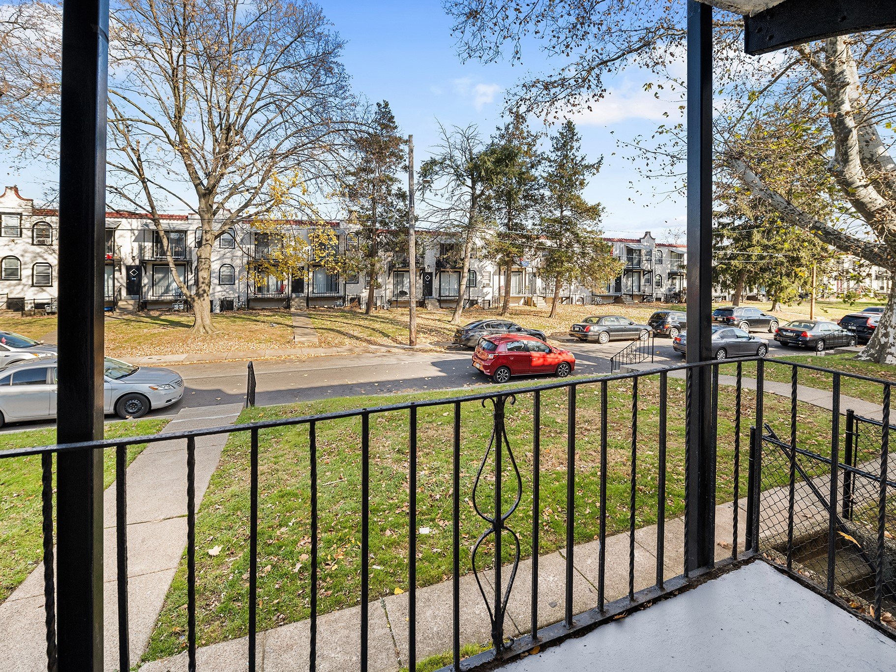 the view from the balcony of a residence with cars on the street