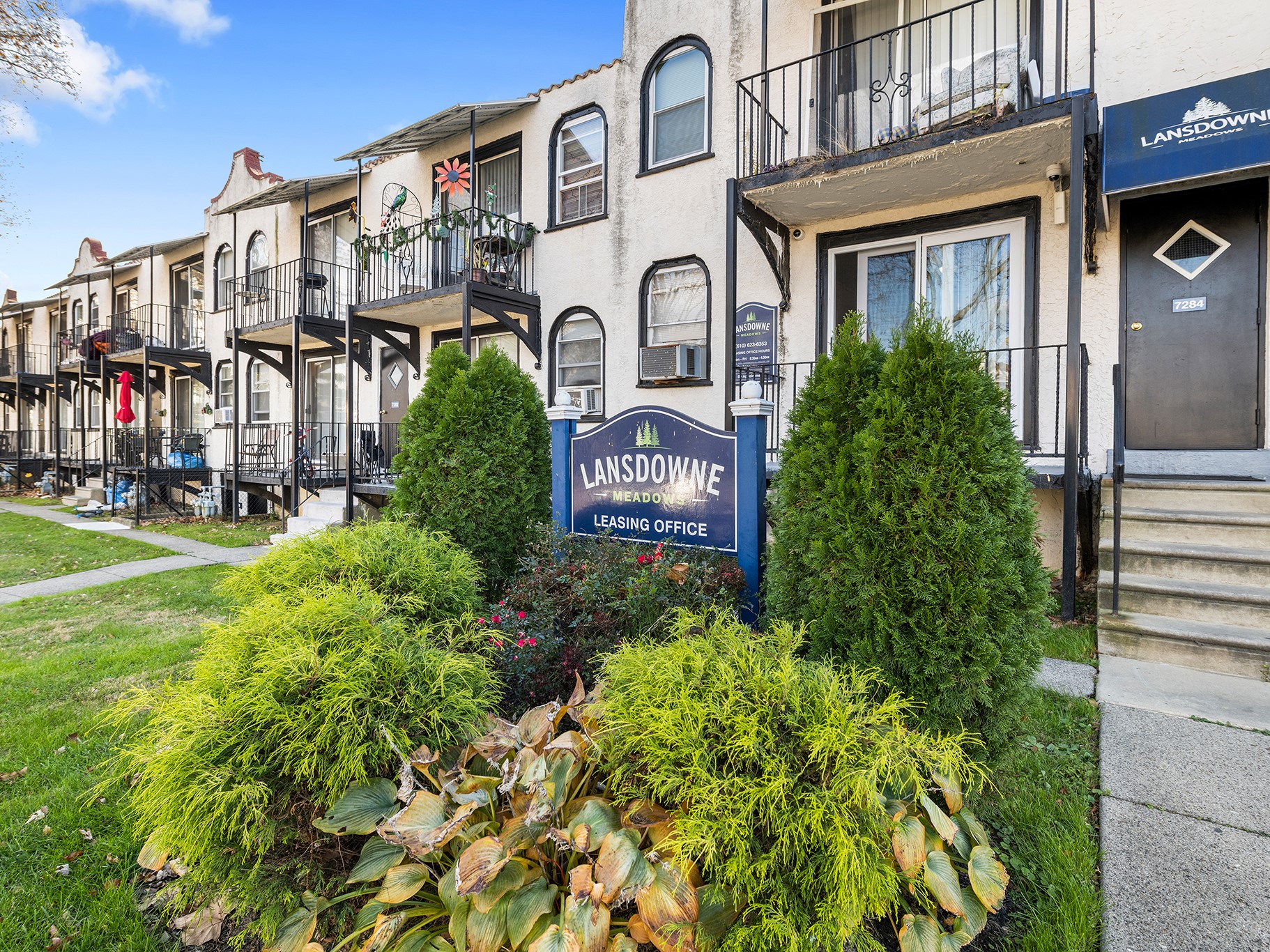 a building with a sign in front of some bushes and plants