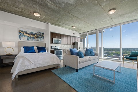 A bedroom with a large bed and a couch with a view of the city.