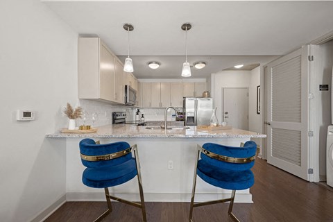 A kitchen with a white counter top and blue chairs.
