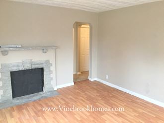 an empty living room with a fireplace and a wooden floor