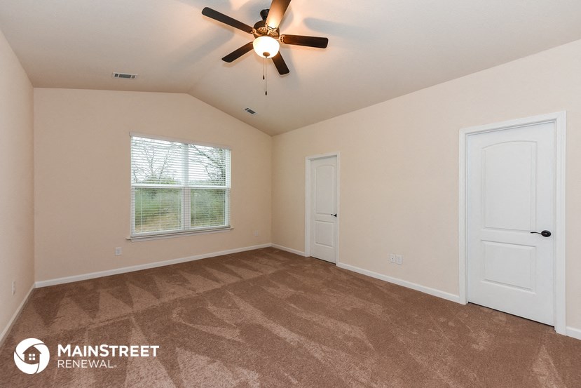 the master bedroom has a carpeted floor and a ceiling fan