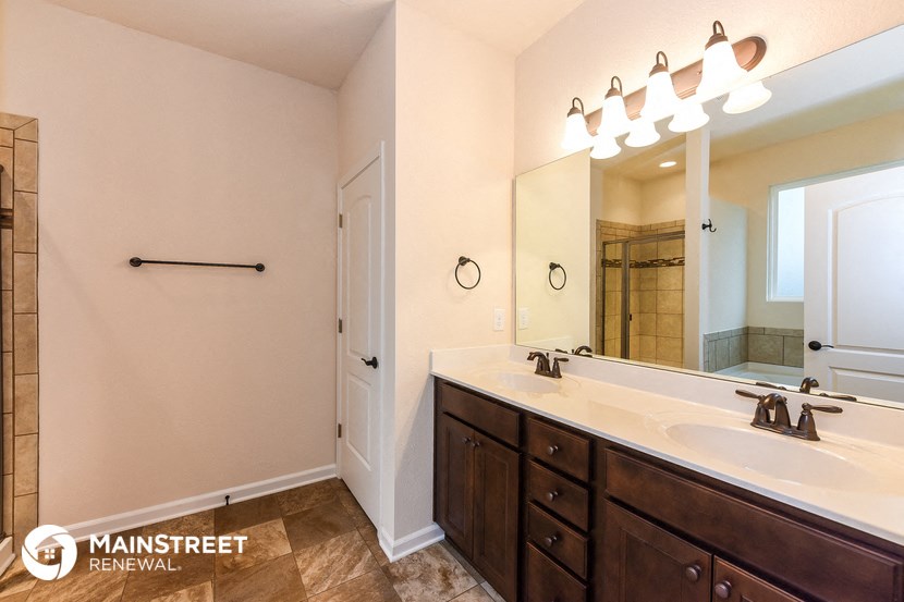 the master bathroom has a large vanity and a large mirror