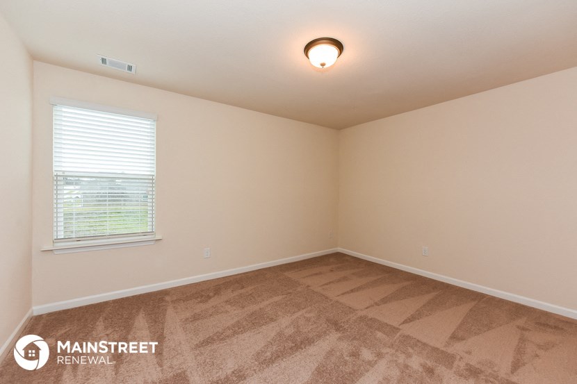the spacious living room of a house with carpet and a window