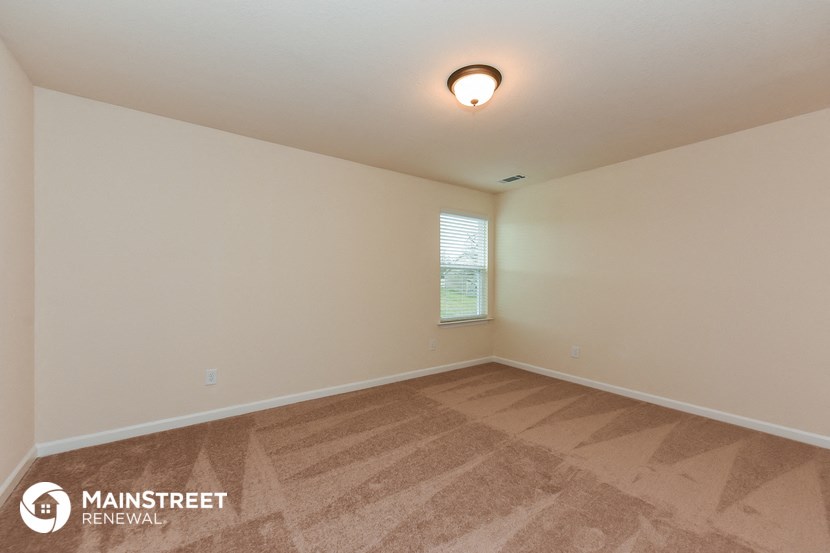 the spacious living room with wood flooring and a window