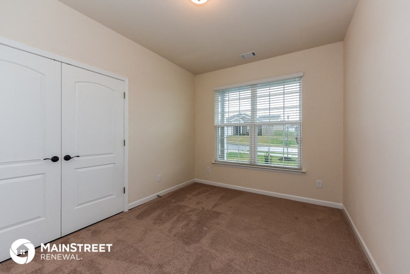 a bedroom with a closet and a window and a white door