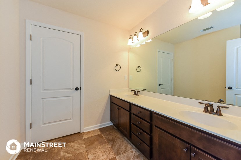 the master bathroom has a large vanity and a large mirror