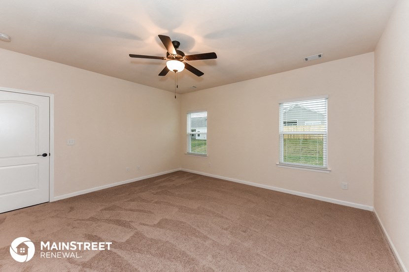 the spacious living room with ceiling fan and carpeting