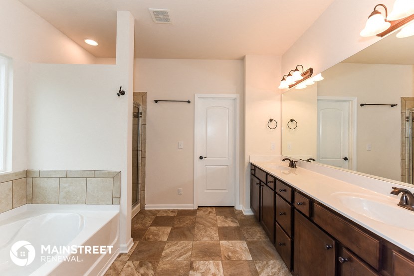 the master bathroom has a large tub and a large vanity with two sinks