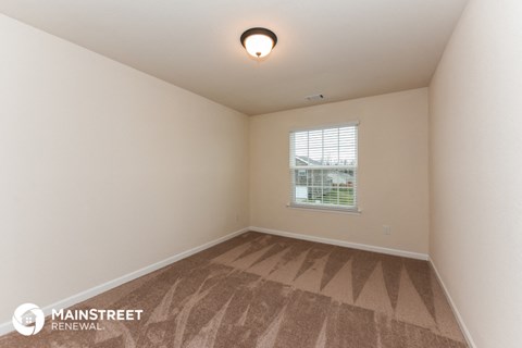 the living room of an apartment with carpet and a window