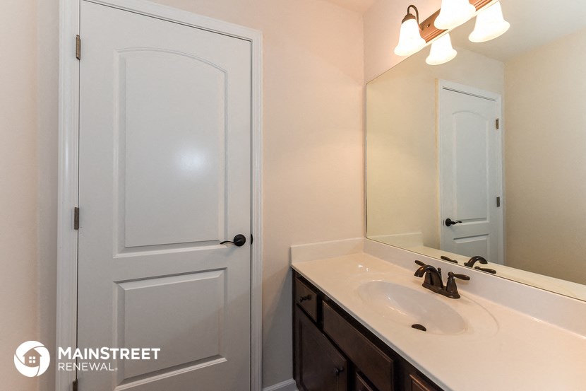 a bathroom with a sink and a mirror and a white door