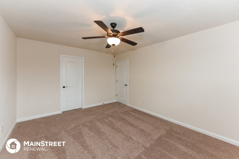 the spacious living room with carpet and ceiling fan