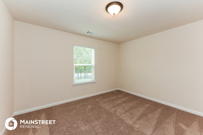 the spacious living room with carpeting and a window