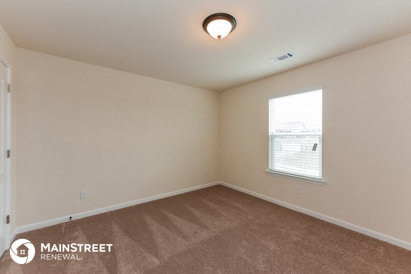 the spacious living room with carpeting and a window