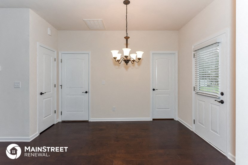 an empty living room with white doors and a chandelier