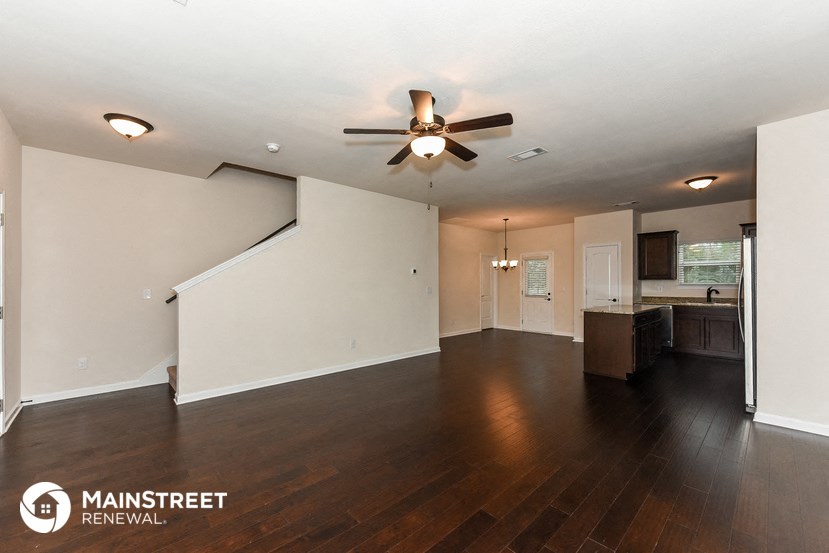 the living room and dining room with hardwood floors and a ceiling fan