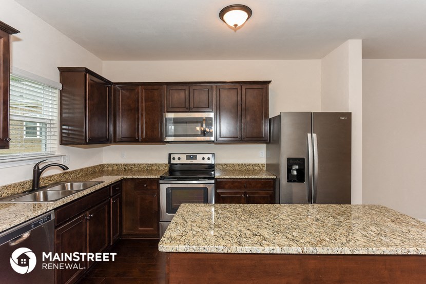 an updated kitchen with granite counter tops and stainless steel appliances