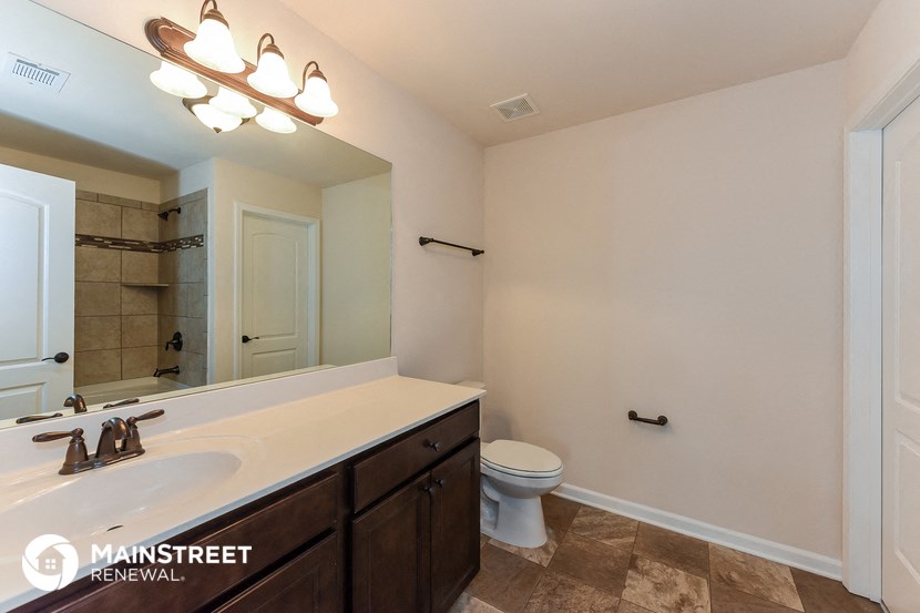 the master bathroom has a large mirror and a sink and a toilet