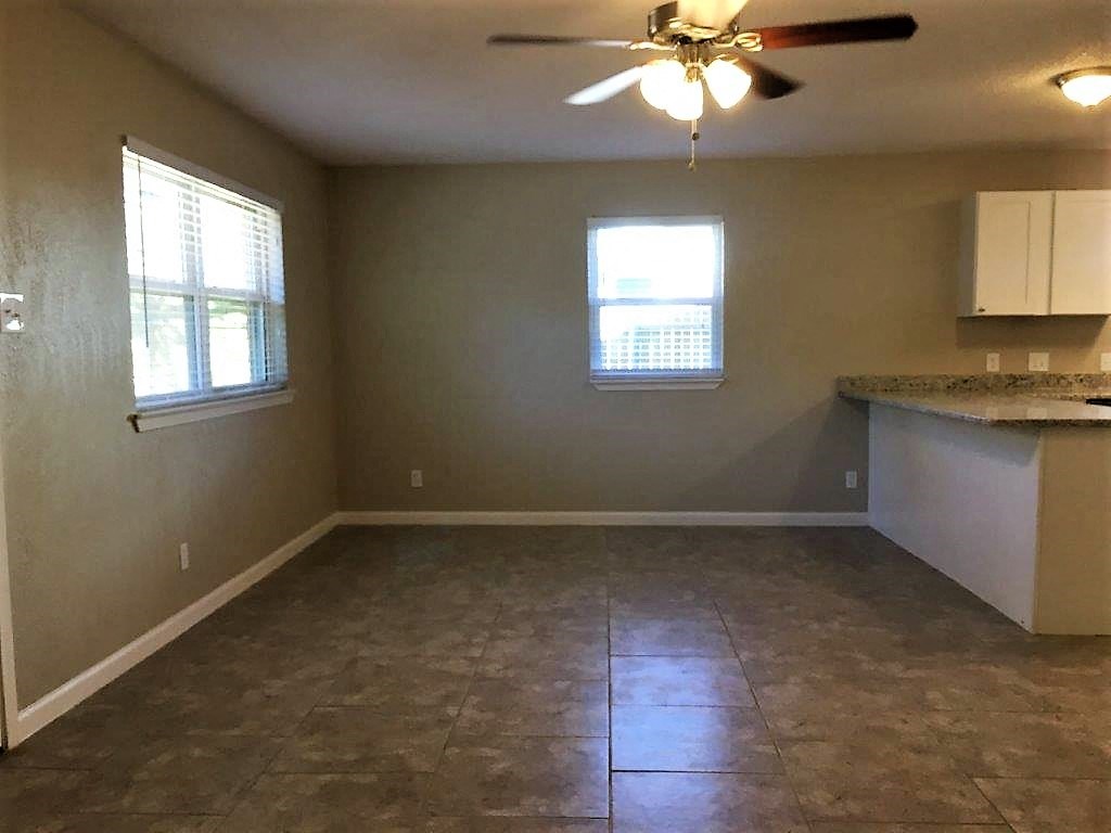 an empty living room with a ceiling fan and a window