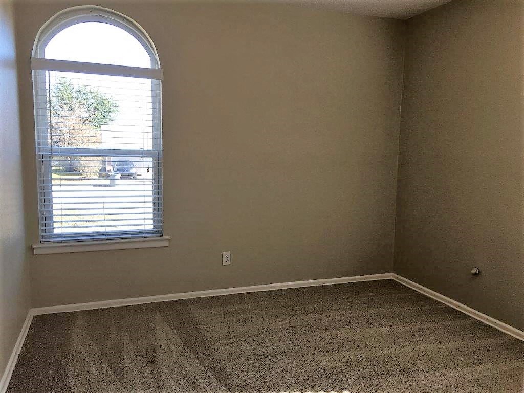 an empty room with a window and a carpet