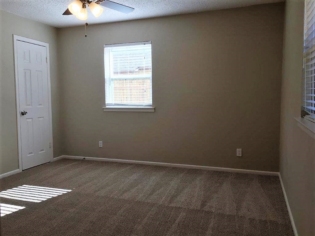 an empty room with a window and a ceiling fan