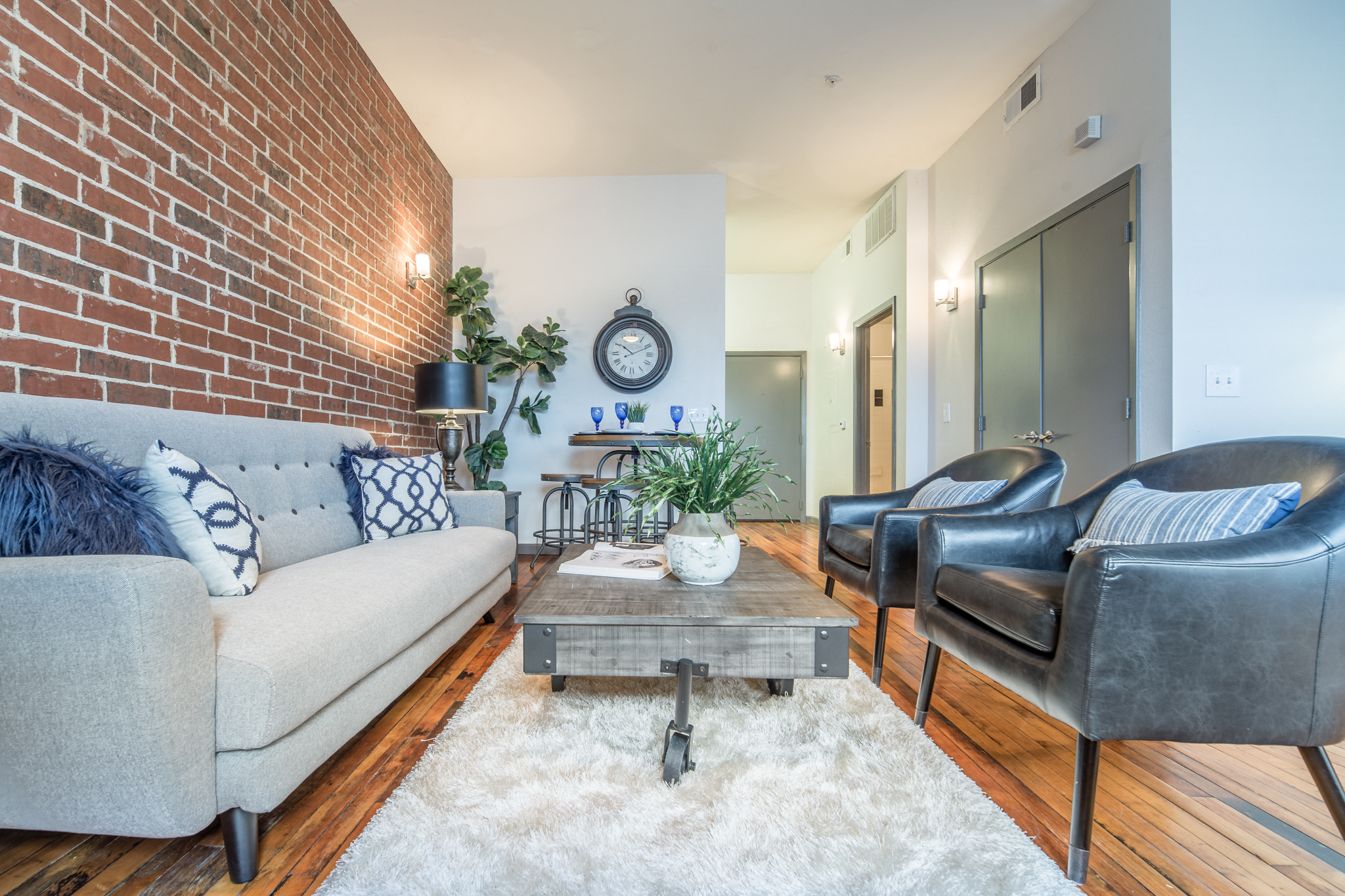 a living room with a couch and chairs and a brick wall