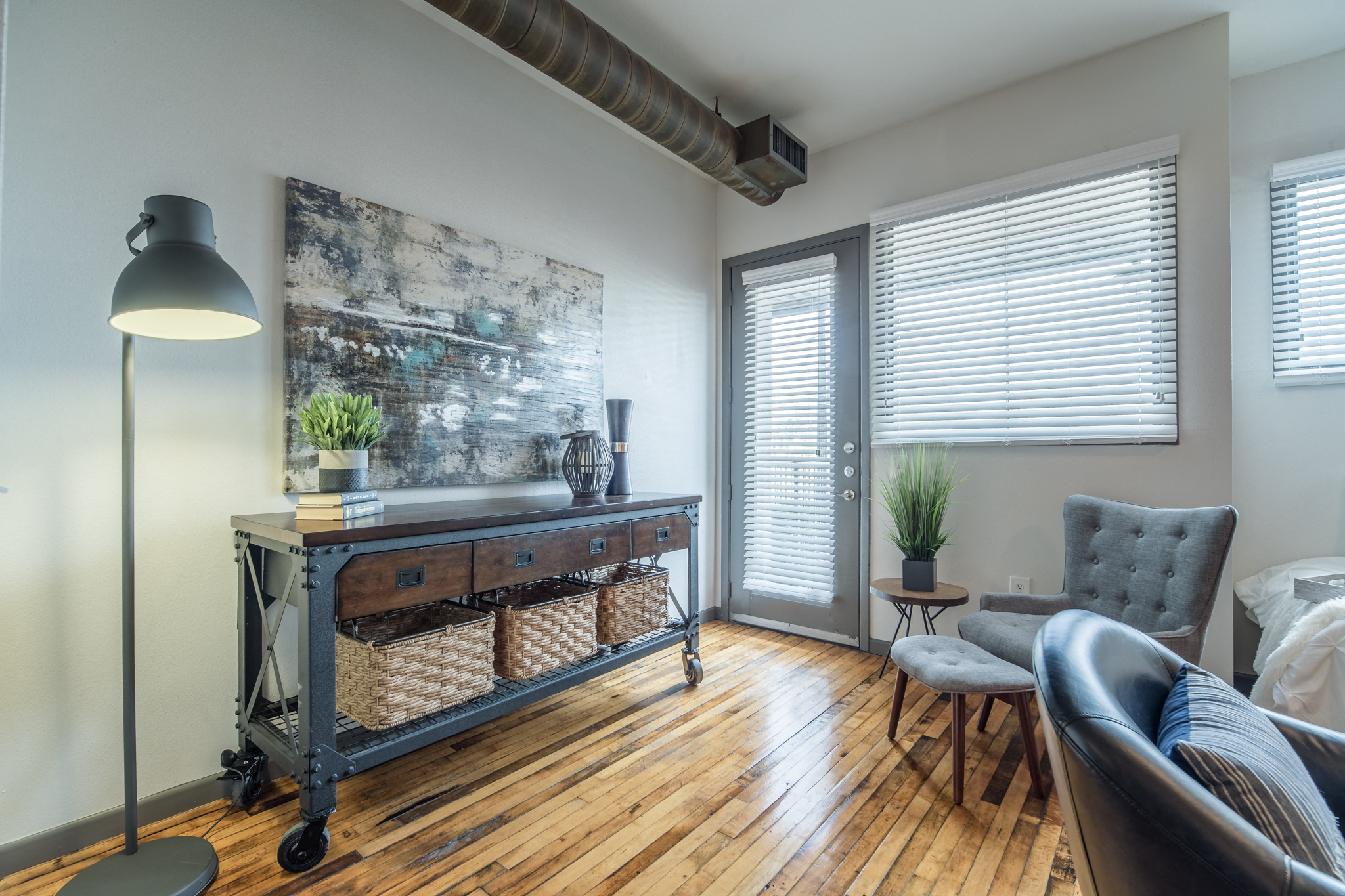 an open living room with a couch and a table with a lamp and a window