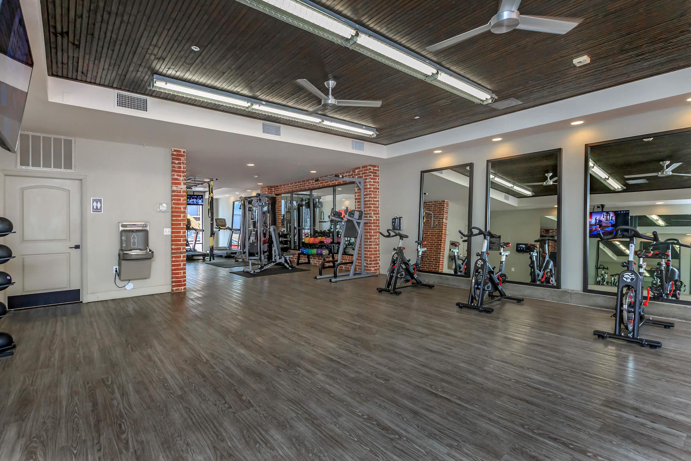 a gym with exercise equipment and mirrors in a building with wood floors