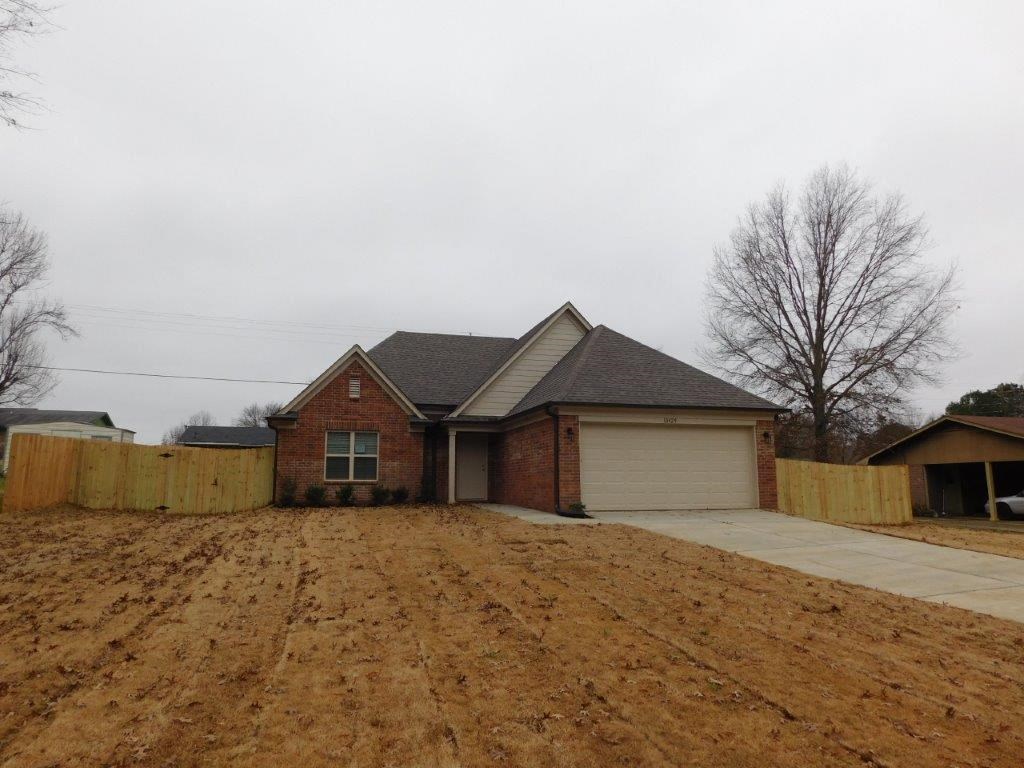 a brick house with a garage and a dirt lot
