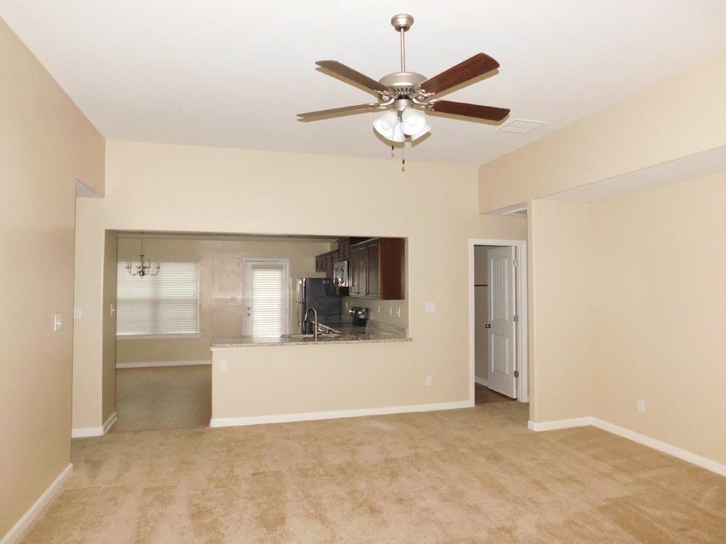 an empty living room and kitchen with a ceiling fan