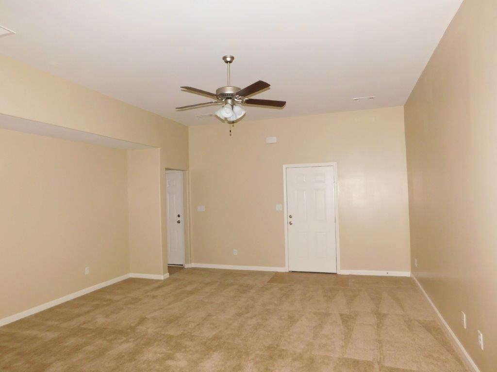 an empty living room with a ceiling fan