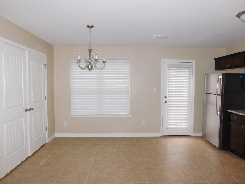 an empty kitchen with a refrigerator and a door