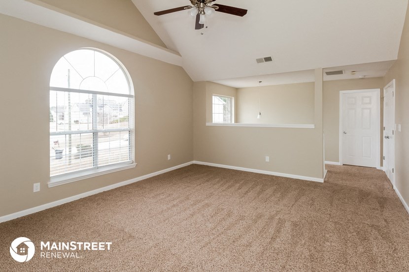 an empty living room with a ceiling fan and a large window