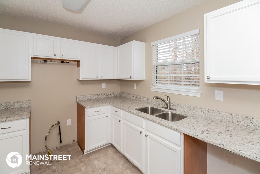a kitchen with white cabinets and granite counter tops and a sink