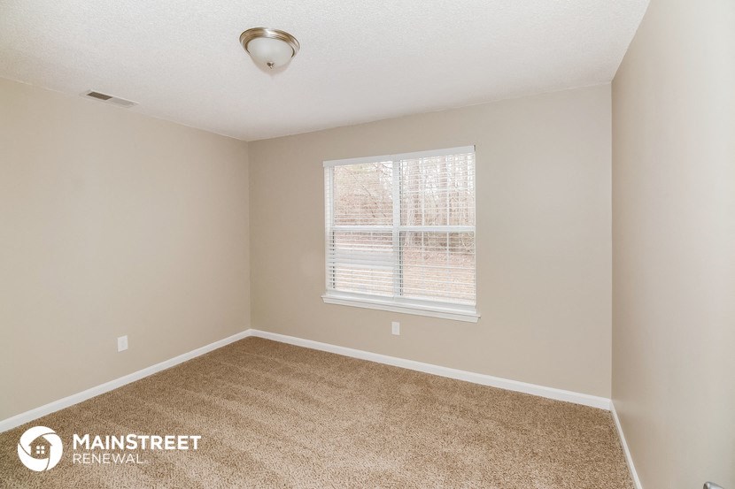 the spacious bedroom with carpeted flooring and a window