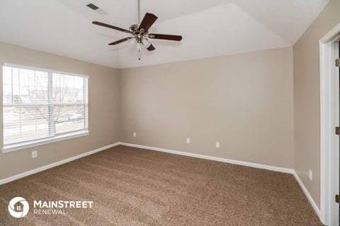 the spacious living room with carpet and ceiling fan