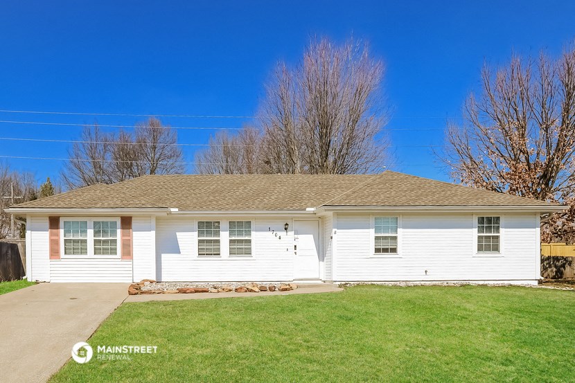 a white house with a green lawn and a blue sky
