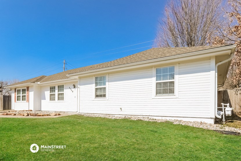 a white house with a green lawn and a blue sky