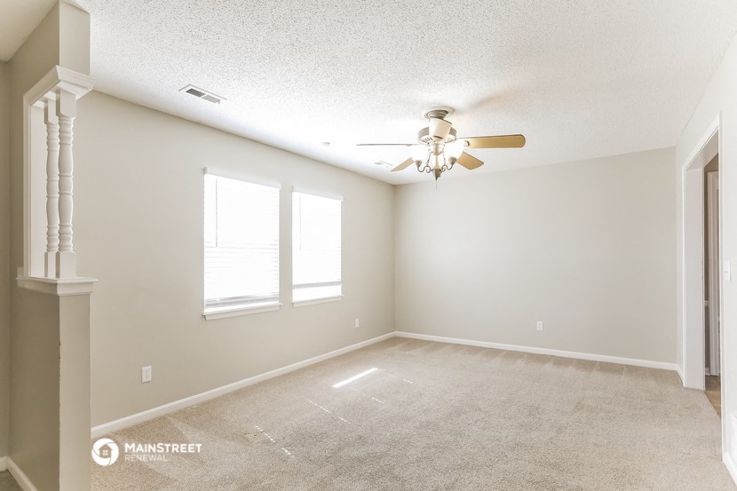 an empty living room with a ceiling fan and a window