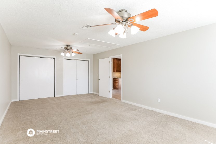 an empty living room with a ceiling fan and a closet